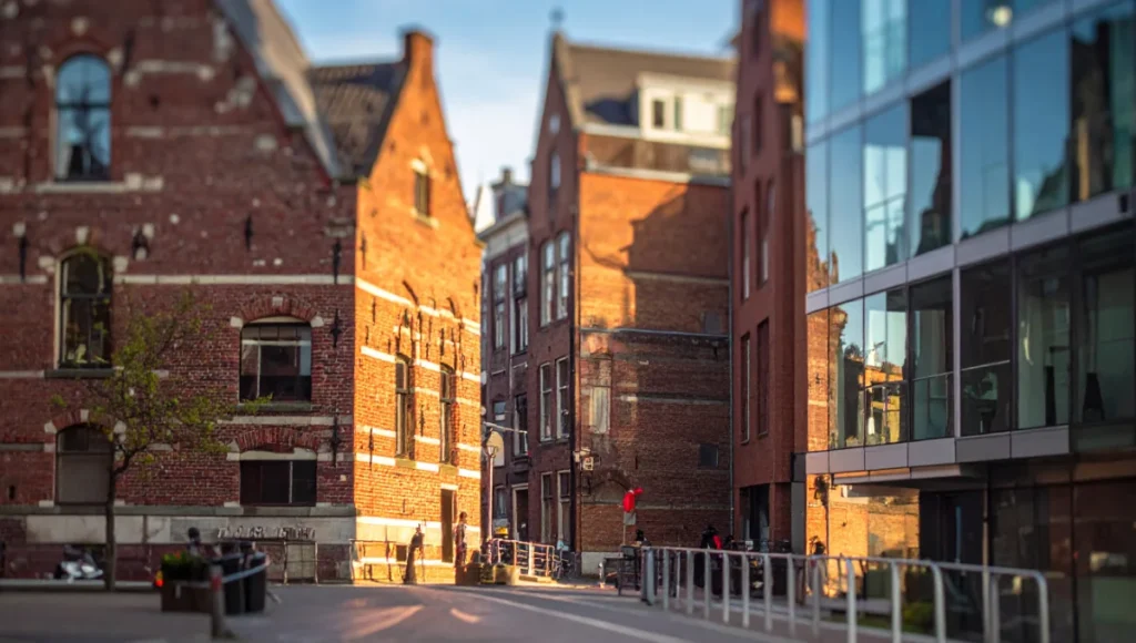 Ultra-realistic architectural photography of Rotterdam's hybrid urban landscape via 24mm tilt-shift lens in golden hour, showcasing post-digital collage elements like tropical plants, metallic pipes, and tectonic textures of masonry and steel-glass for spatial narrative enhancement.