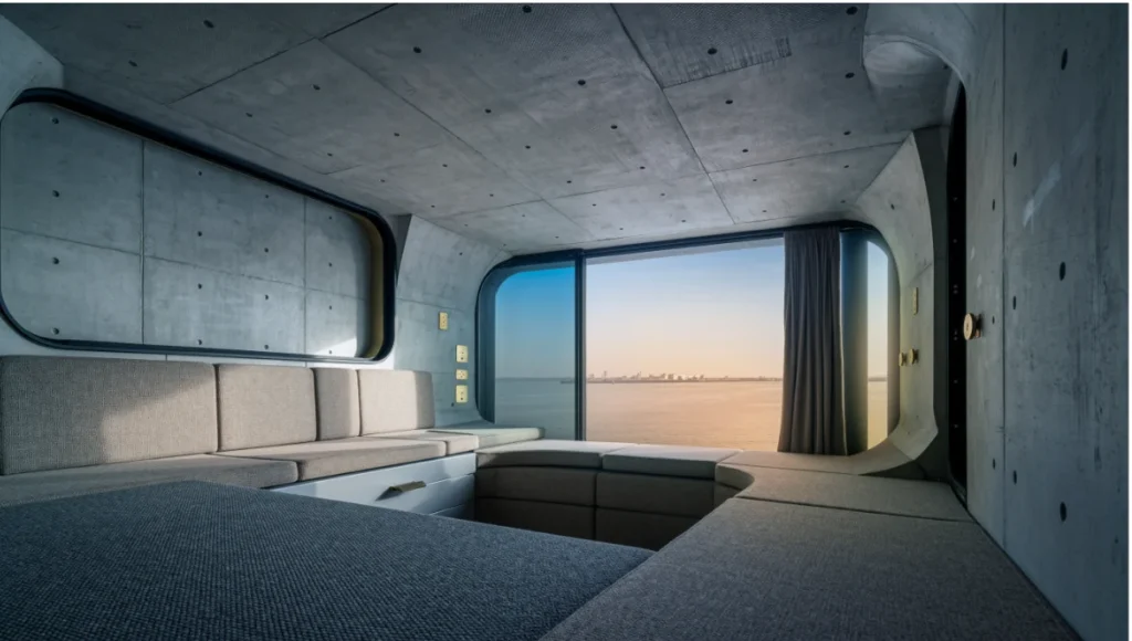Ultra-realistic architectural interior photograph of Nuvira Space Chronos Pod modular bedroom in Rotterdam Harbor, featuring biophilic fractal patterns, circadian smart glass lighting in golden hour transition, raw concrete and brushed brass textures, soft curved refuge corner with high-back seating, 24mm tilt-shift lens, neuro-architecture for stress reduction and peak physiological alignment.