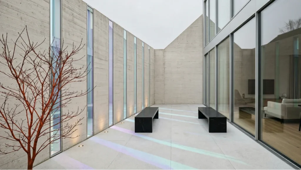 Nuvira Space NEURO-SYNC PERIMETER concept project in Copenhagen — minimalist walled residential garden featuring dichroic glass panel wall inserts casting prismatic Nordic light across Bornholm granite flush-threshold flooring, monolithic Nero Marquina thermal mass benches, single Acer palmatum specimen, and 1800K recessed ground lighting — biophilic neuro-architecture designed to counteract Seasonal Affective Disorder through circadian light sculpting and chromatic restraint.