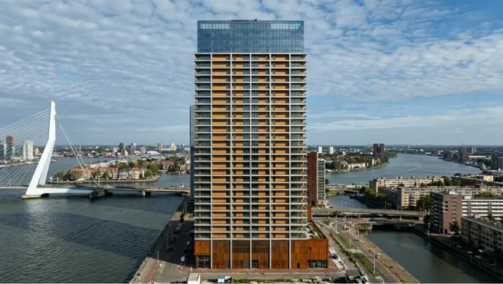 Nuvira Space speculative architectural concept render of Project Maas — a 47-floor hybrid timber-concrete tower on the Rotterdam waterfront, photographed by drone at 180 metres AGL using telephoto compression, showing parametric aluminium louvres casting diagonal shadow bands across CLT facade panels at mid-afternoon October light — internal concept study illustrating drone architecture photography tips for facade shadow documentation.