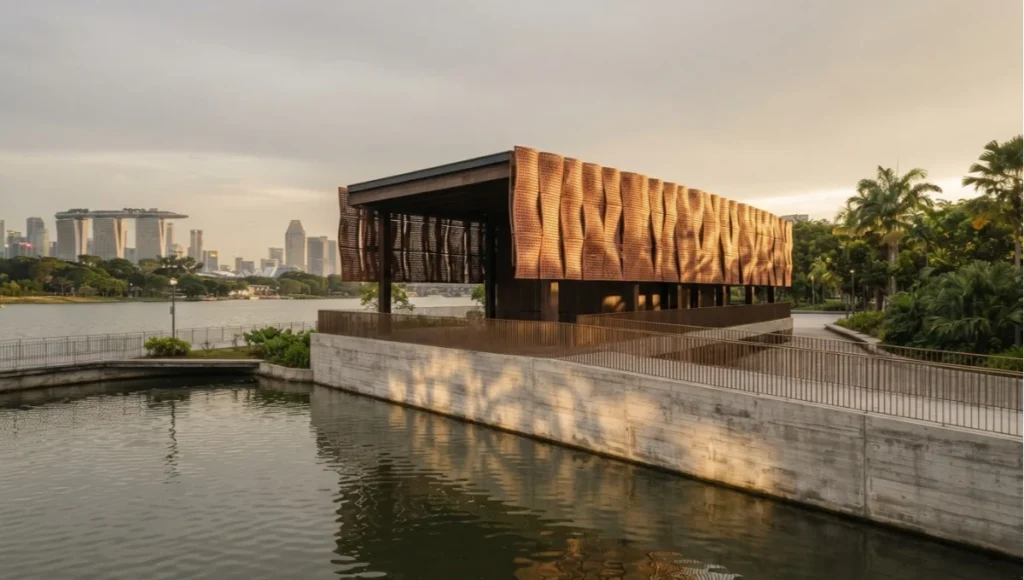 Kallang Verge speculative concept pavilion by Nuvira Space at golden hour on Singapore's Kallang Basin waterfront, showing perforated terracotta rain screen, board-formed concrete plinth, and reflective water feature in a generative ArchViz case study.